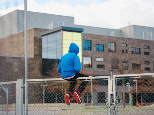 Barneombudet: ungdom som sitter på et gjerde utenfor en bygning