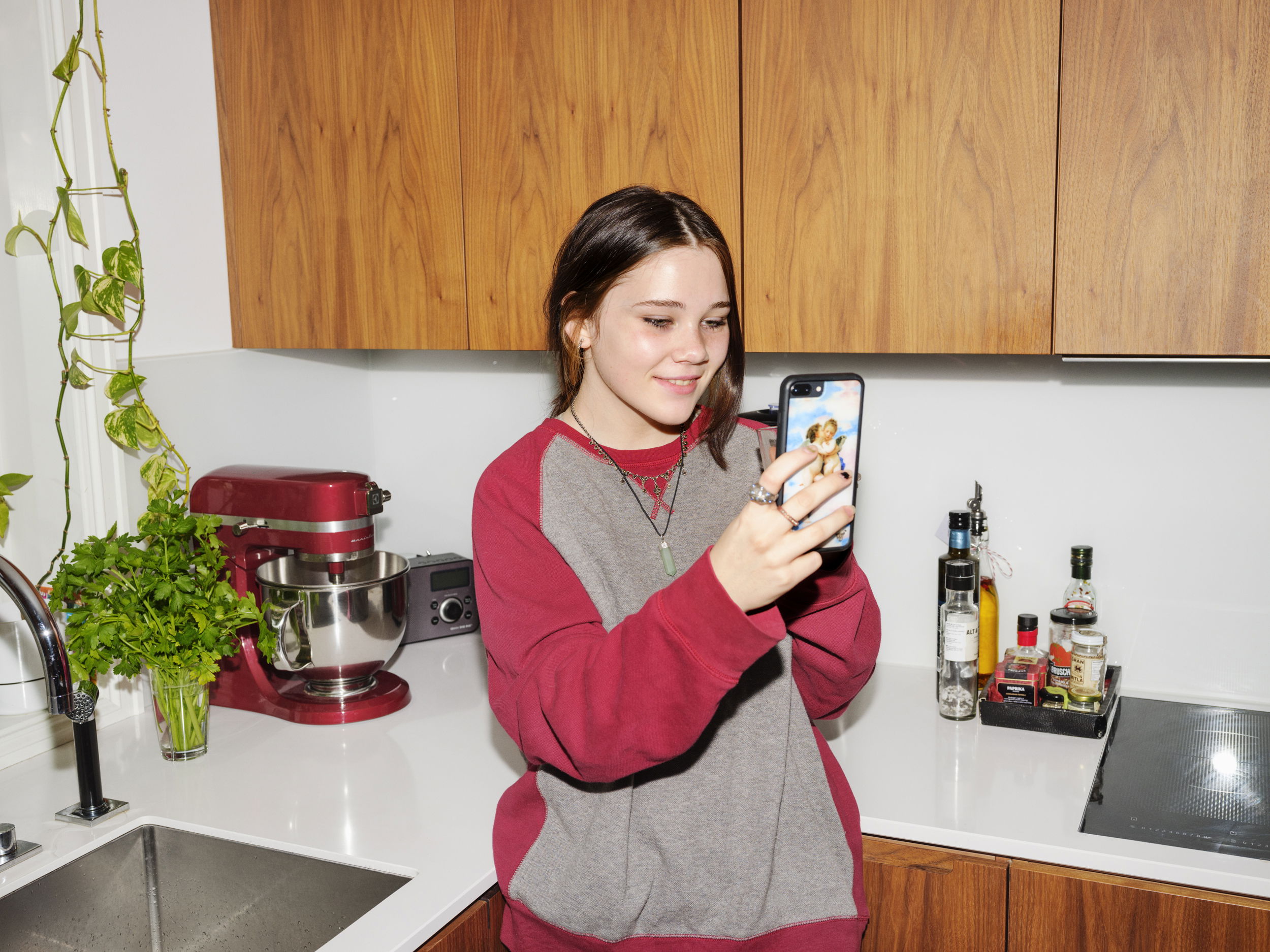 Barneombudet: jente på et kjøkken med telefon