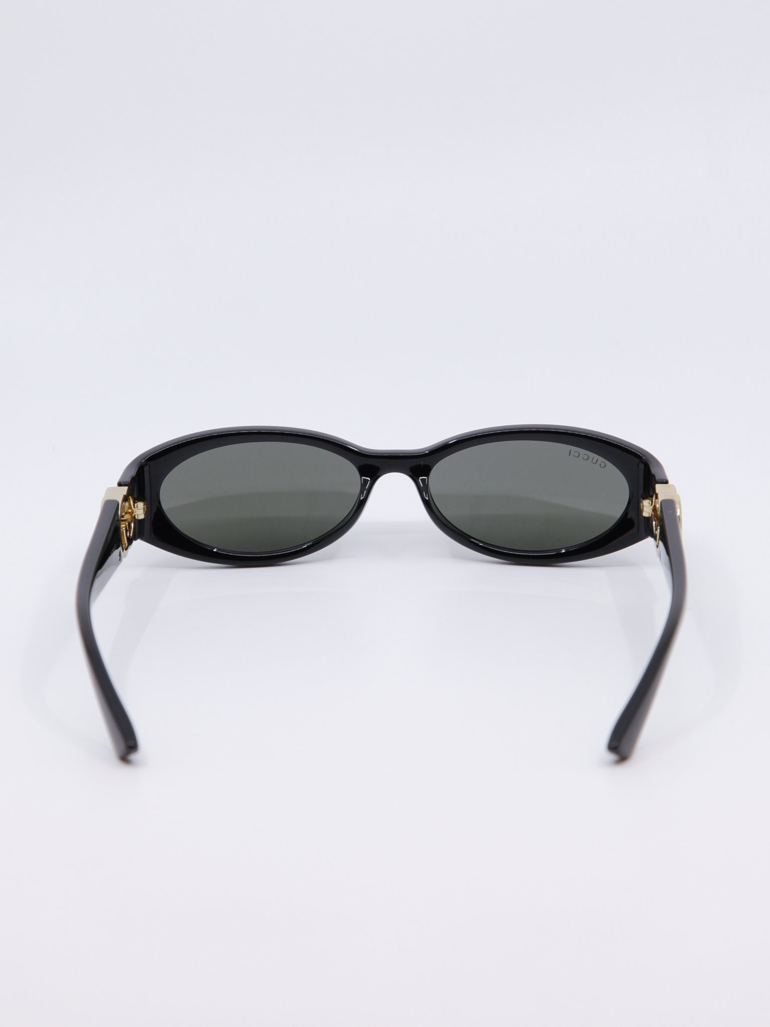 Smal, svart solbrille med vintage-design og gull-logo på brillestengene
