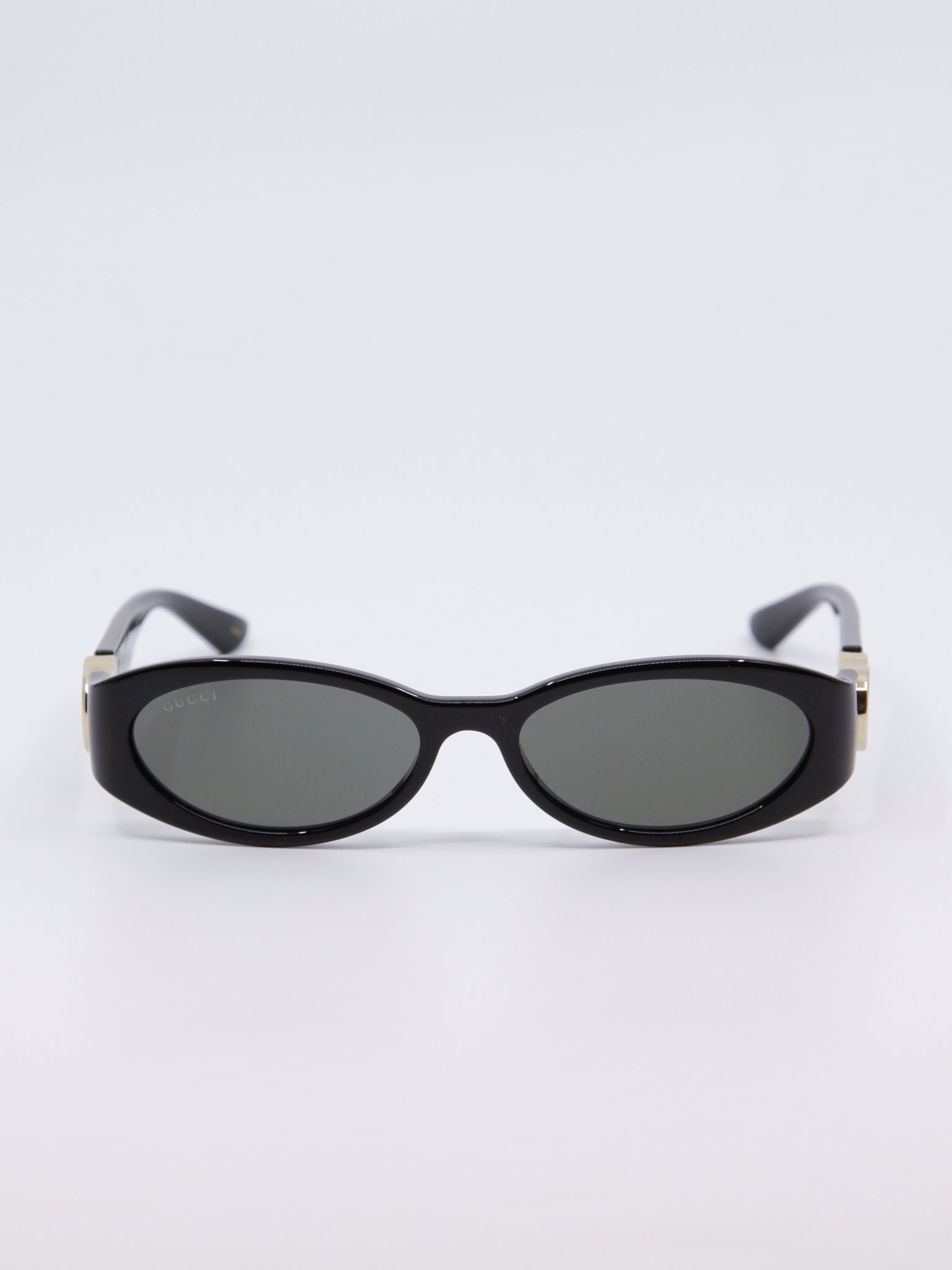 Smal, svart solbrille med vintage-design og gull-logo på brillestengene