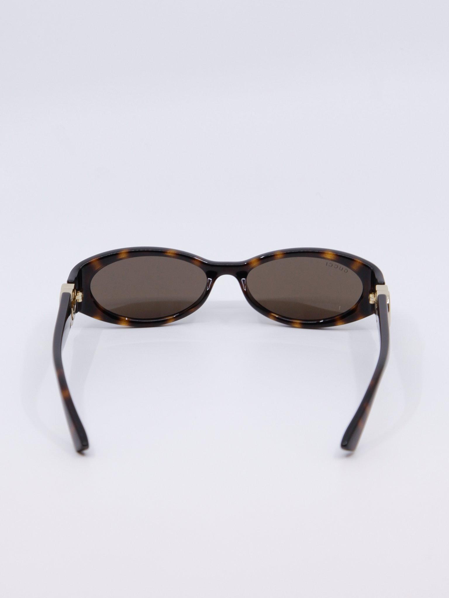Smal, brun solbrille med vintage-design og gull-logo på brillestengene