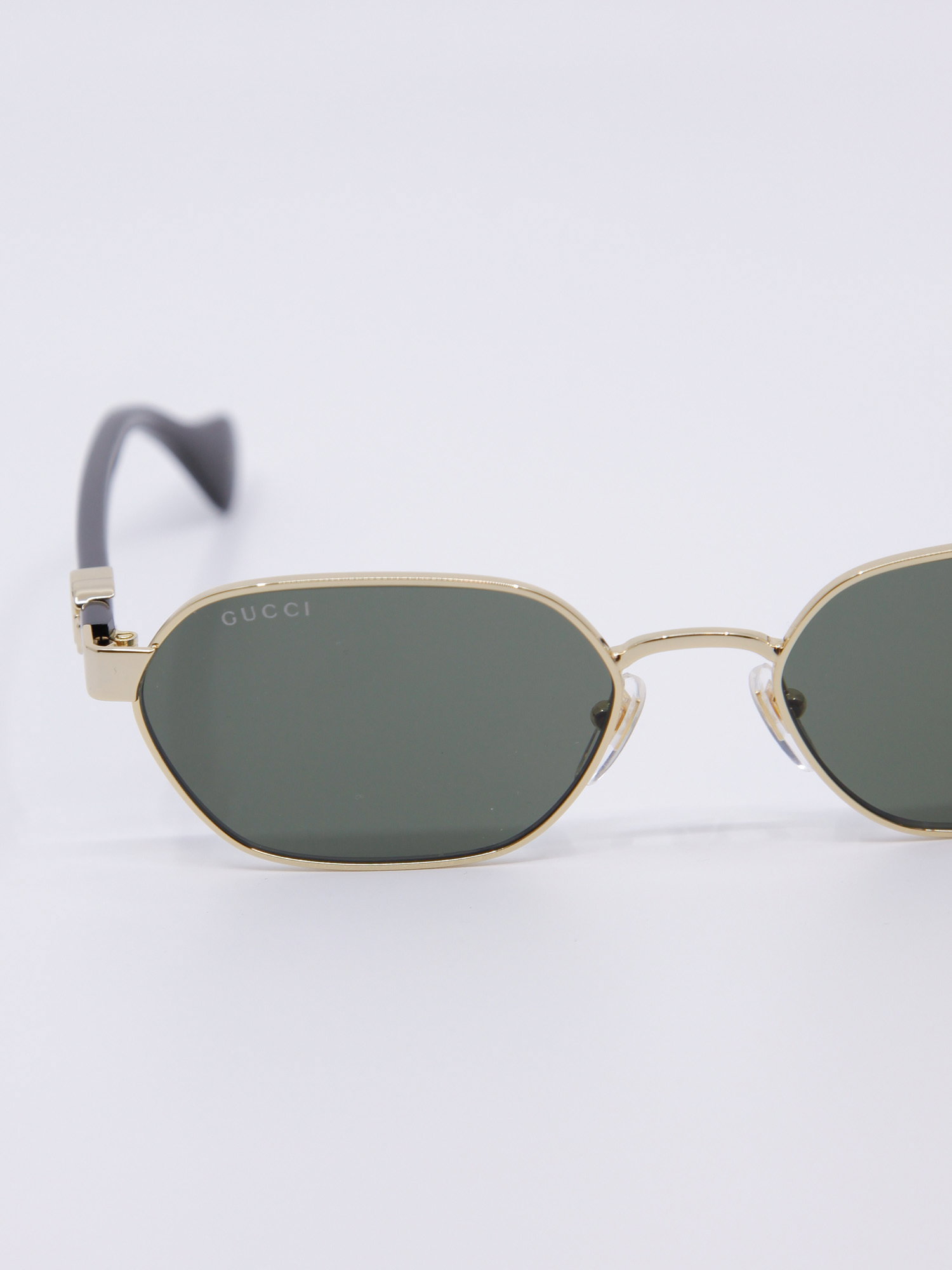 Smal metallsolbrille med gullramme og svarte brillestenger