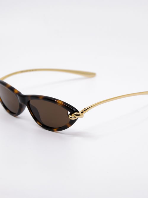 Solbrille i brun med svak cateye fasong og brillestenger i gull