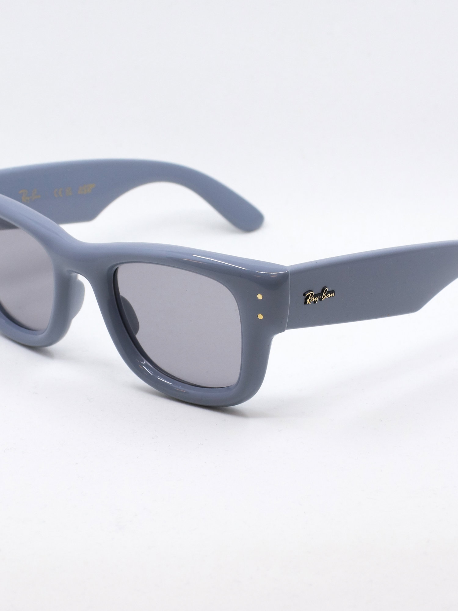 Solbrille med blå, klumpete ramme og lyse solbrilleglass