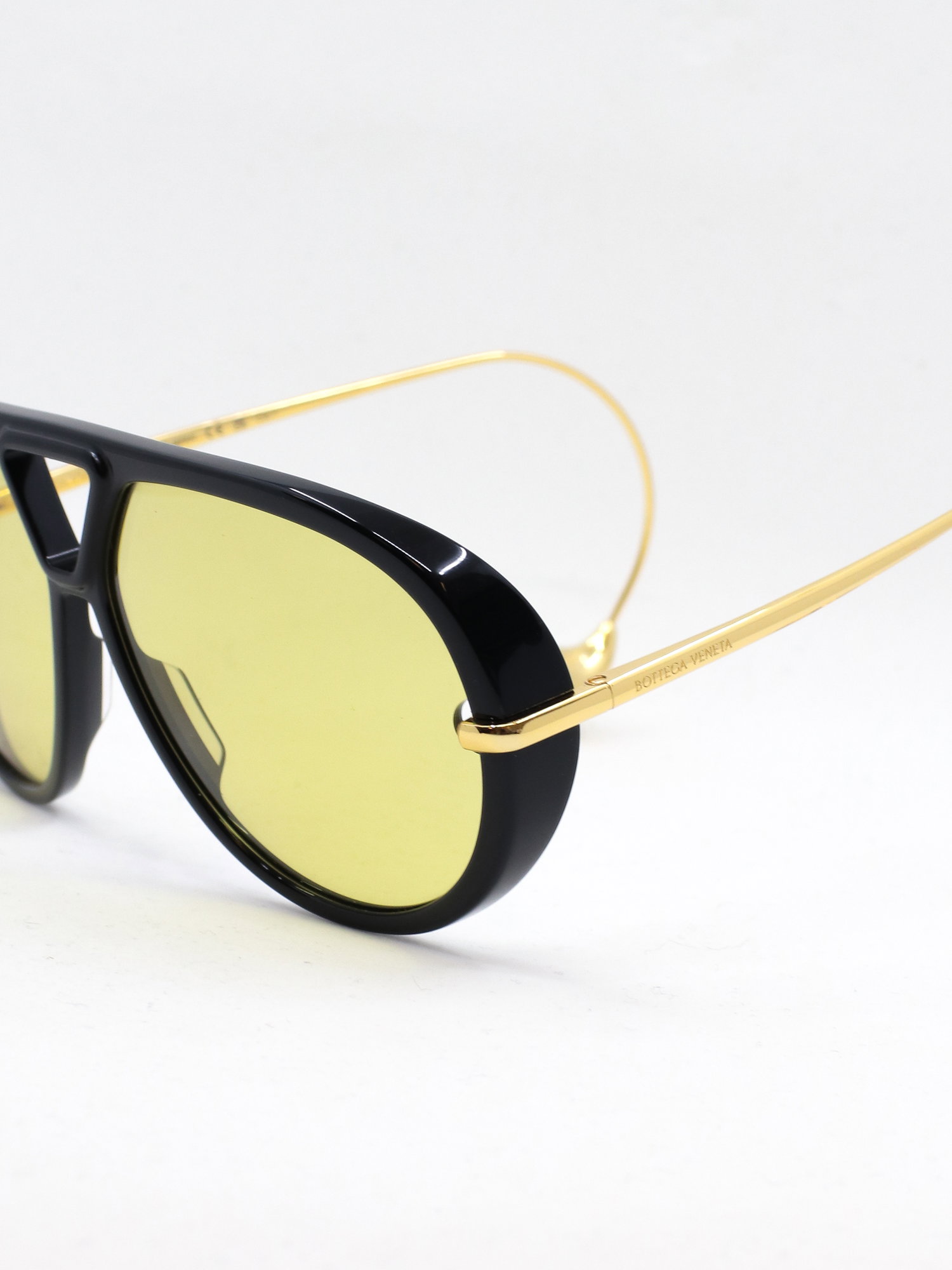 Pilotsolbrille i svart med gule glass og brillestenger med perleformede tupper