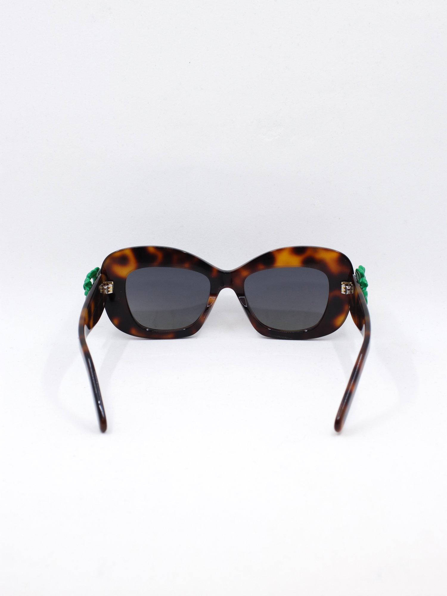 Brun solbrille med cateye fasong og en trebladet kløver-detalj i stangfestet