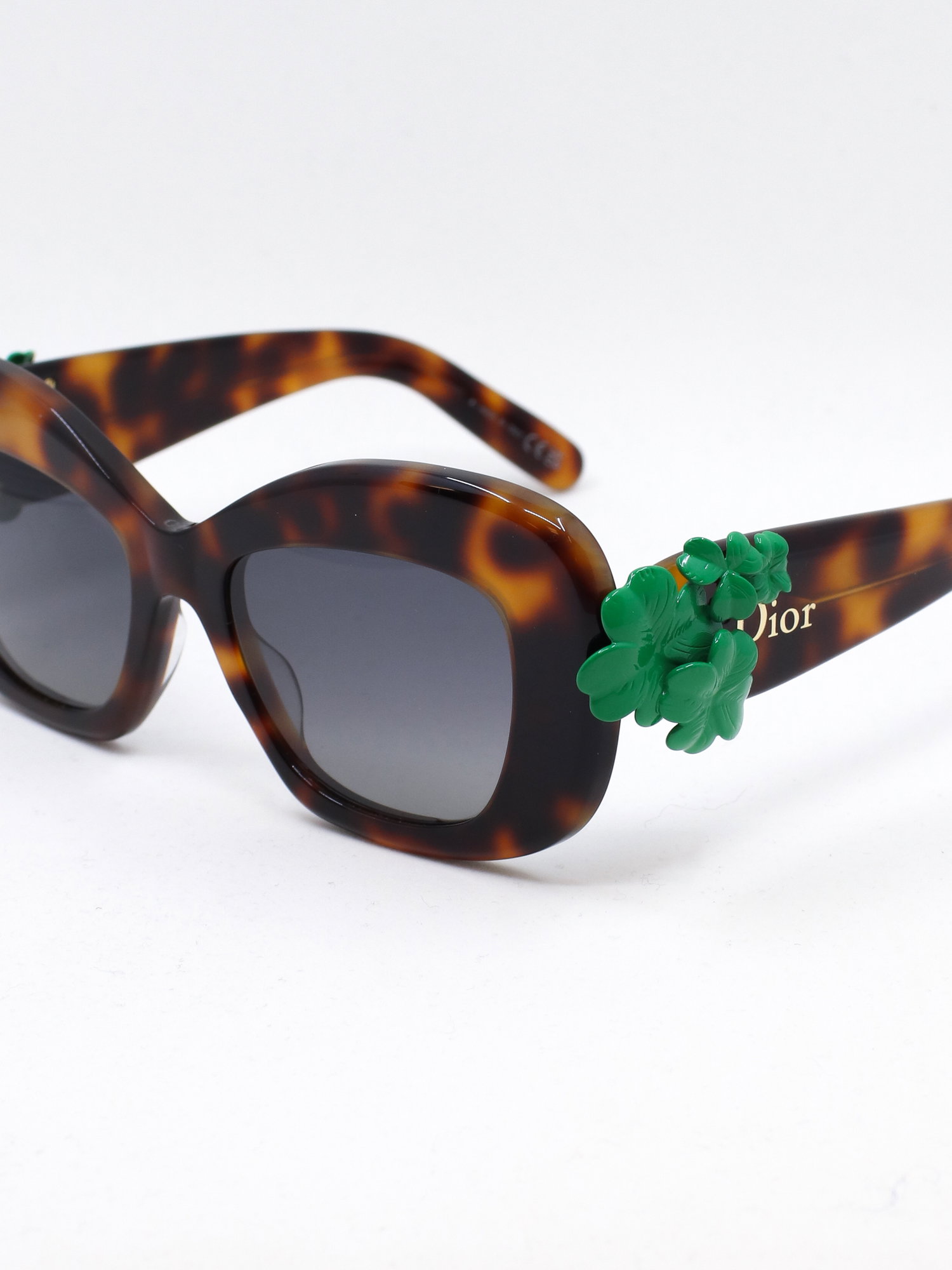 Brun solbrille med cateye fasong og en trebladet kløver-detalj i stangfestet