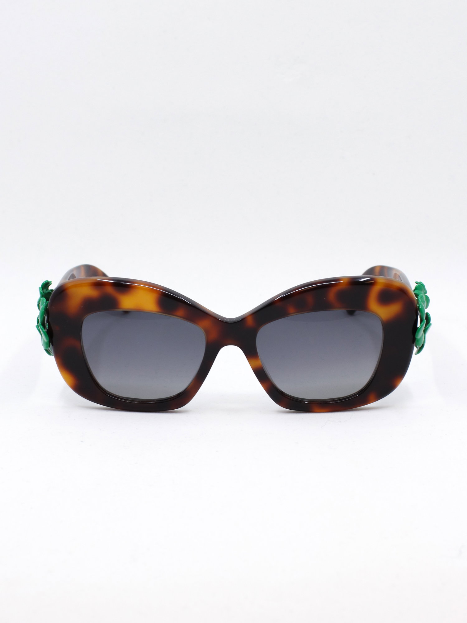 Brun solbrille med cateye fasong og en trebladet kløver-detalj i stangfestet