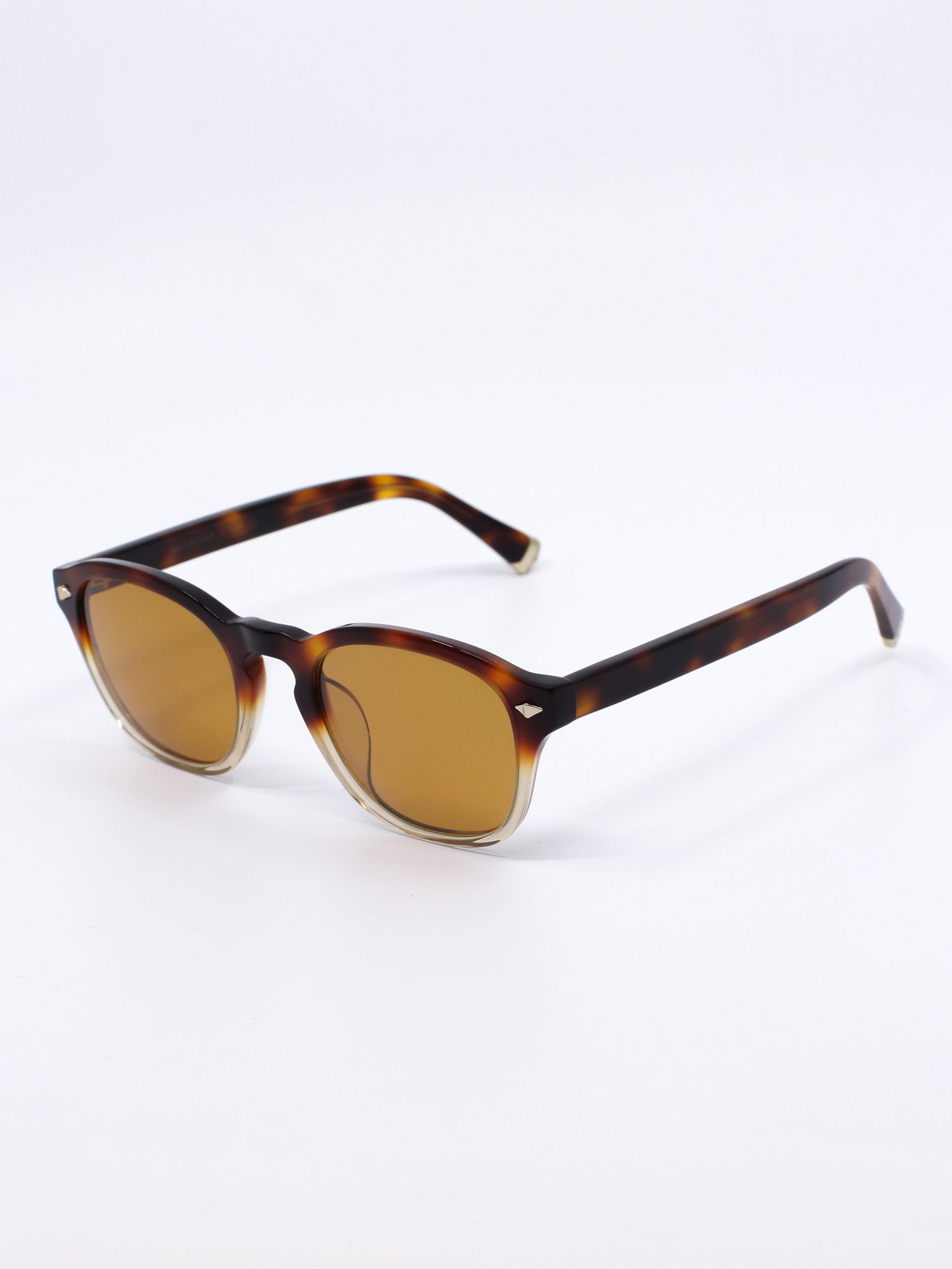 Stilig solbrille fra Brunello Cucinelli med firkantet fasong, med lette avrundede kanter. Solbrillen har en ramme med brun farge i øvre del som går over i en lys, transparent nedre del. Brune solbrilleglass og metalldetaljer i gull.