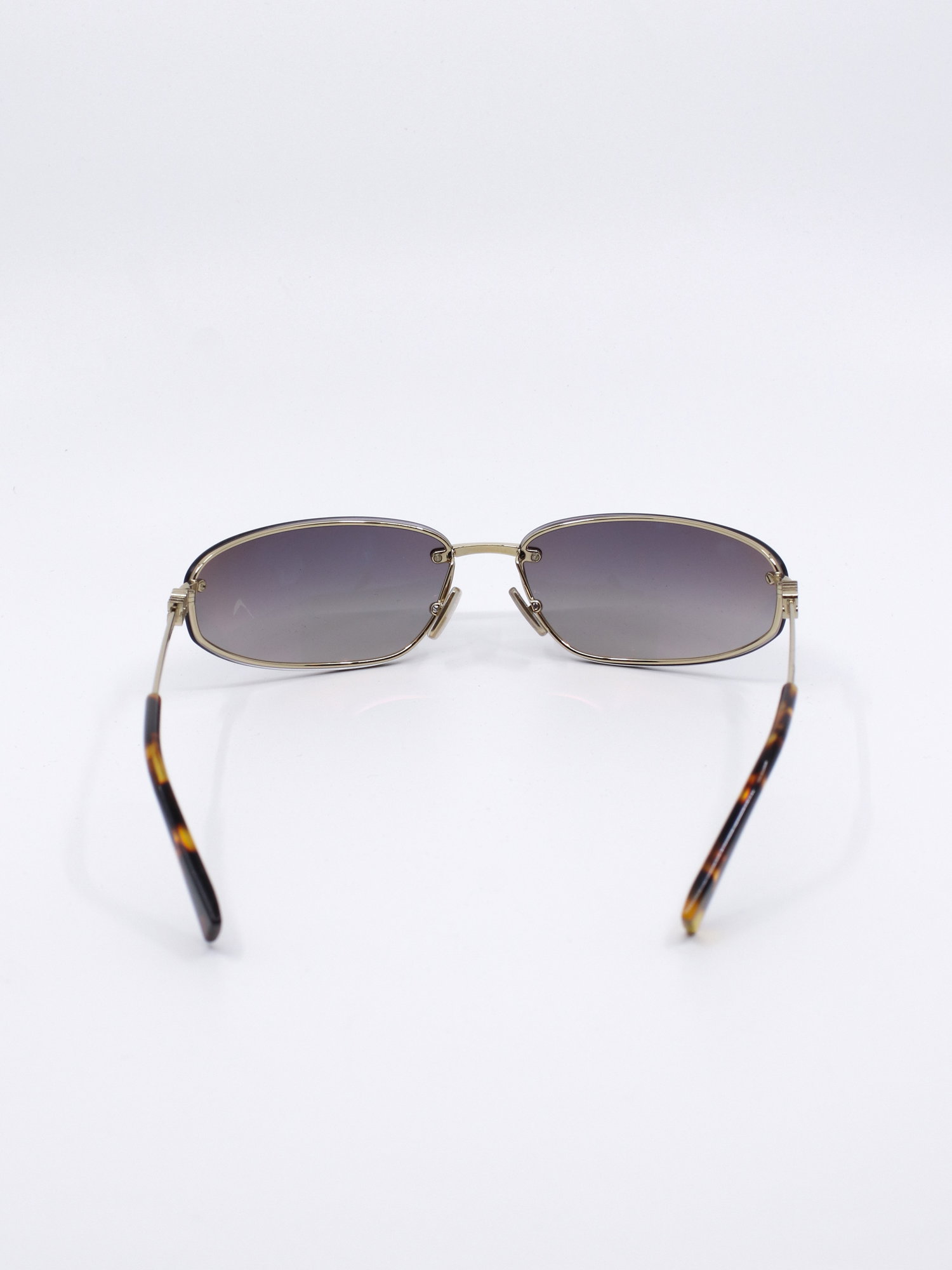 Solbrille med futurisk design. Solbrilleglass med gradert farge og metallstenger i gull