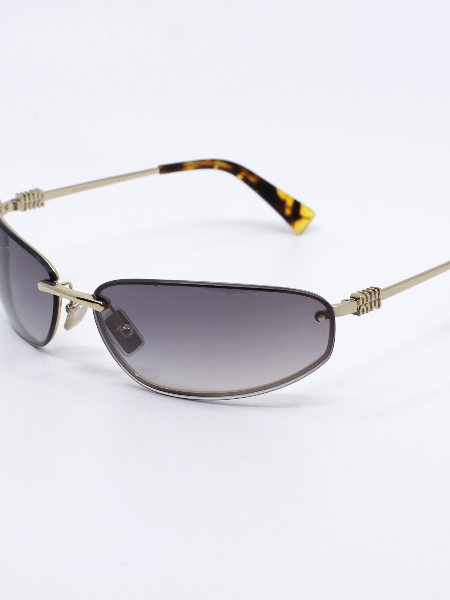 Solbrille med futurisk design. Solbrilleglass med gradert farge og metallstenger i gull