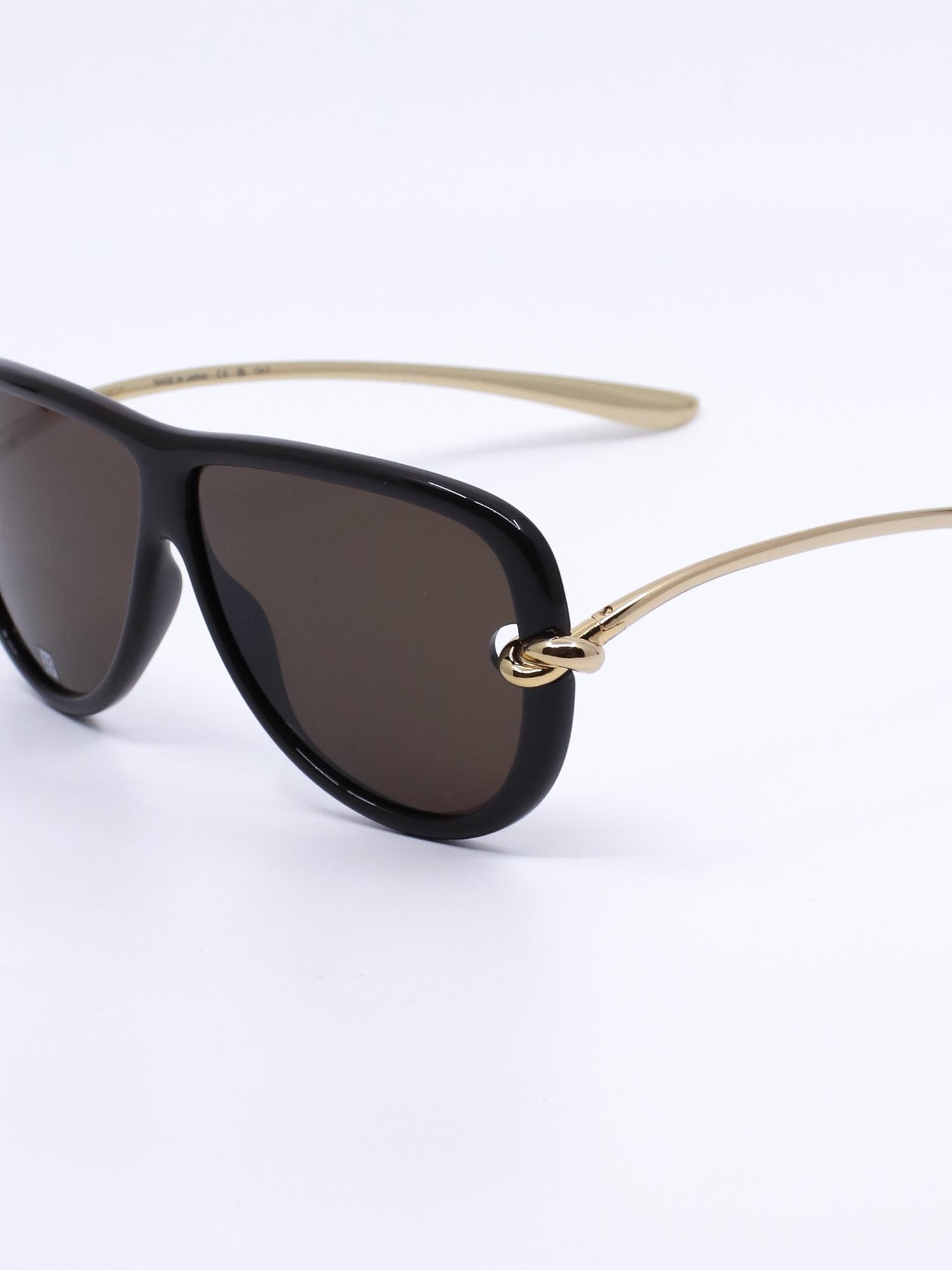 Pilotsolbrille i svart med metallstenger i gull