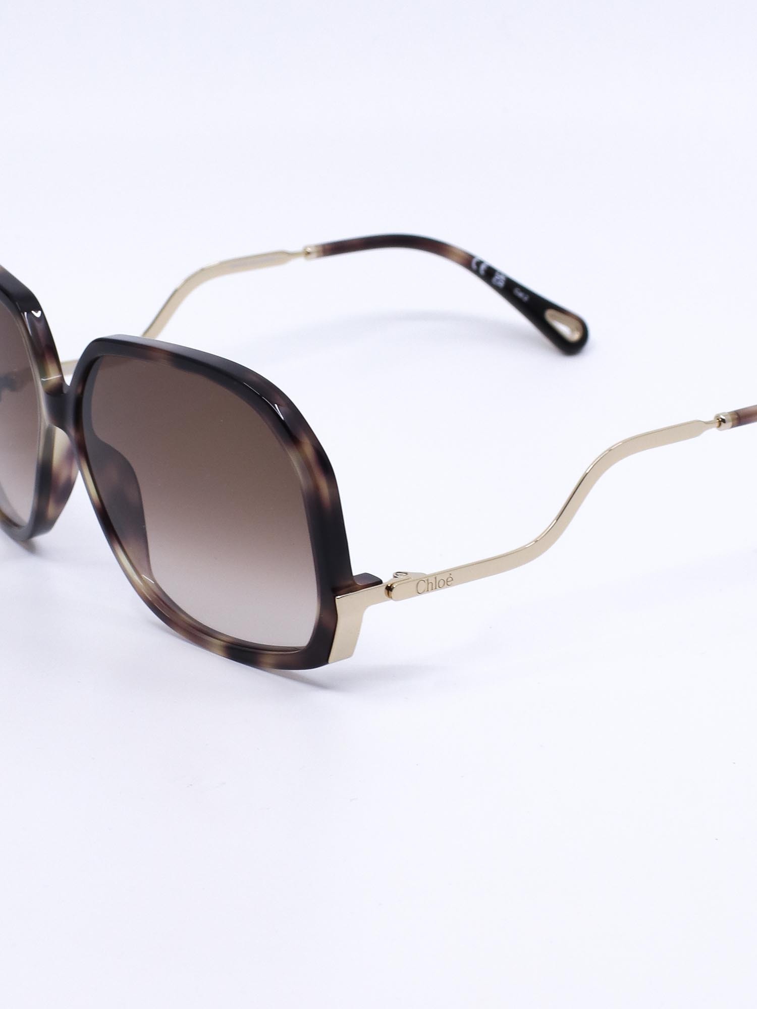 Oversized solbrille med organsik kvadratisk fasong og bølgede brillestenger