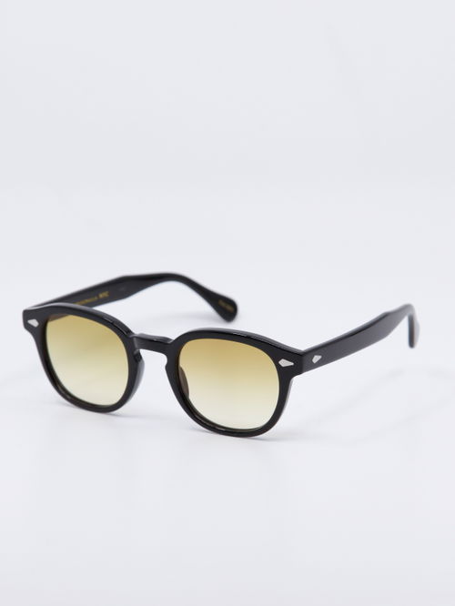 Rund solbrille med sort ramme og  karamell fargede, gradert glass, bilde fra siden