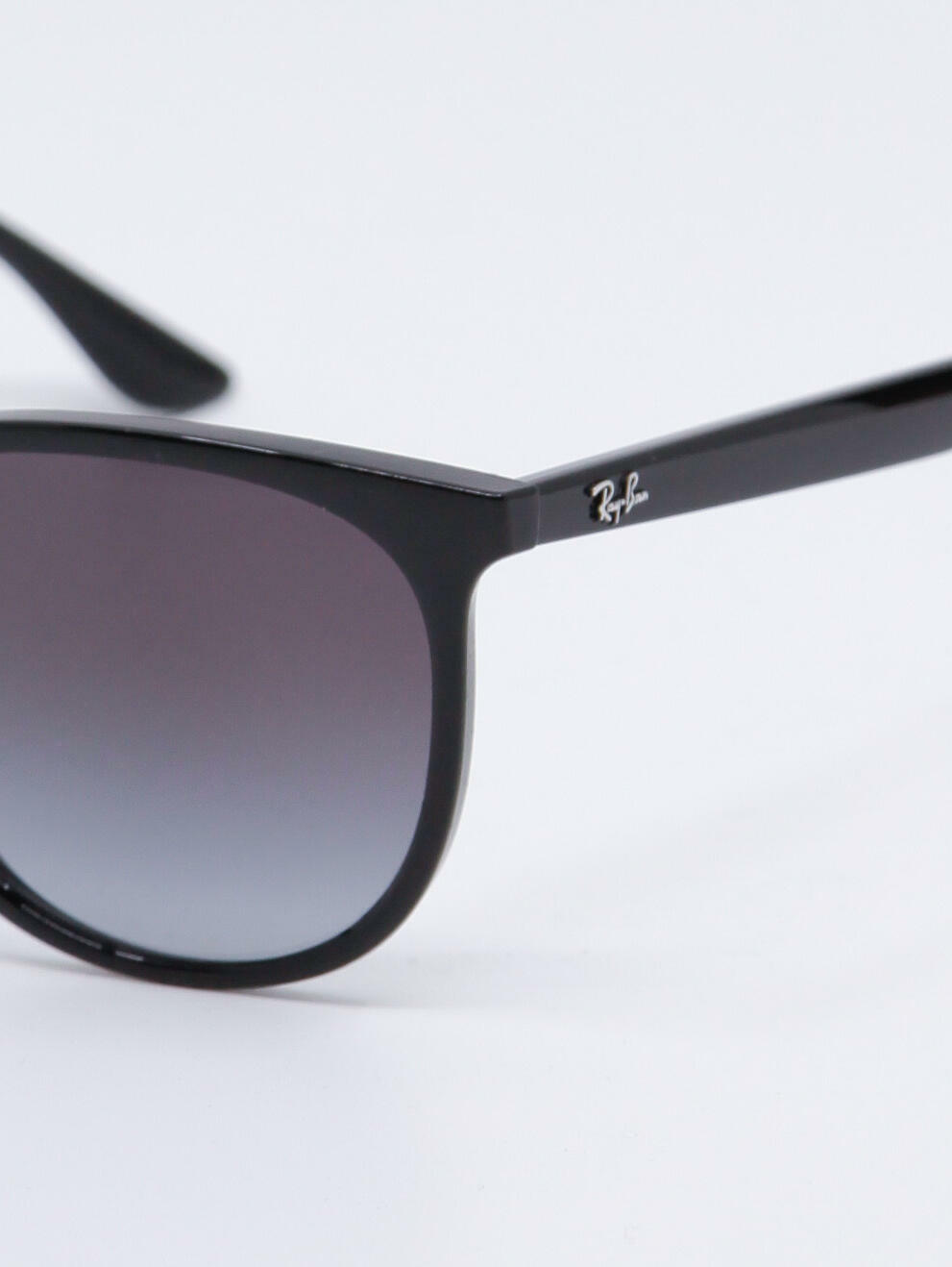 Sort og rund solbrille med svart ramme og gråblå glass, bilde nær