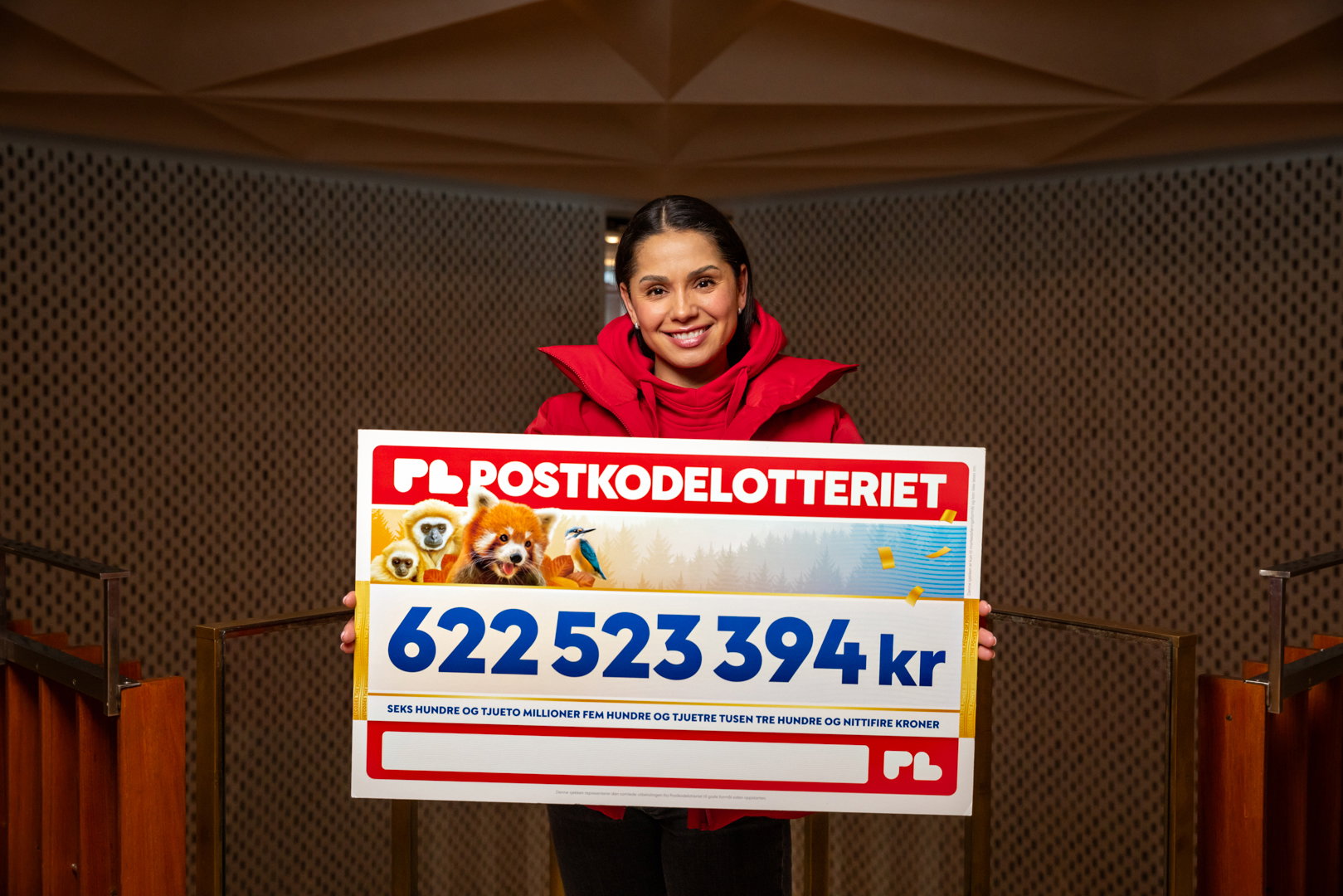 Kvinne står med en stor sjekk.